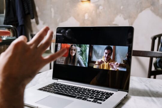 a team member sitting at a laptop, speaking on video call with their colleagues. Showing a business using modern internet telephony systems.