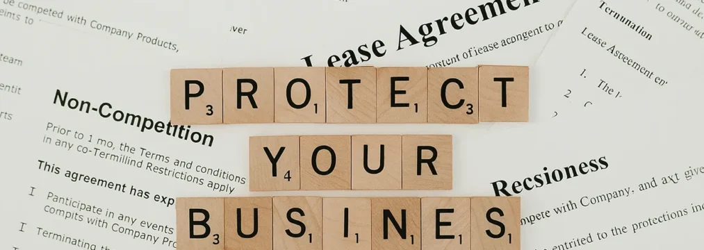 A variety of policy documents spread across a table, with scrabble pieces reading 'protect your business'. ai policy template for business