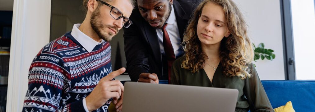 a group of people surrounding a laptop discussing